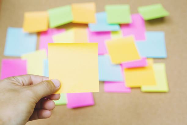 istock close up people holding paper post it in hand stick wall board. paper note 1007843856