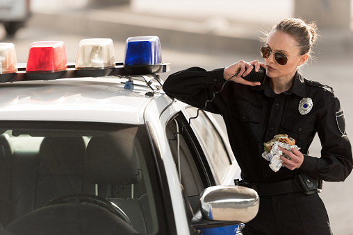grave policía con hamburguesa en la mano hablando en la radio set photo