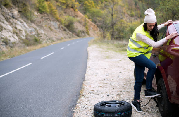 istock Frustrated Female Driver With Tire Iron Trying To Change Wheel 1007856902