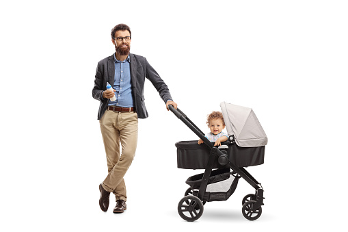 Full length portrait of a father with a bottle of milk and a baby boy in a stroller isolated on white background