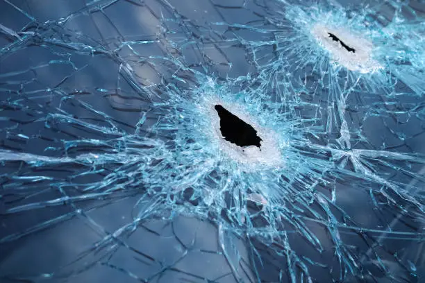 Closeup of a whole and cracked windshield produced by gunshots