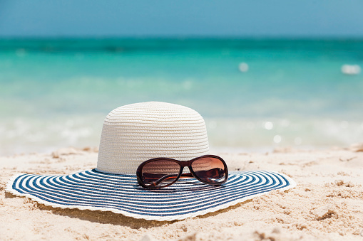 Sun hat and sunglasses on the beach of Grand Bahama island in The Bahamas.