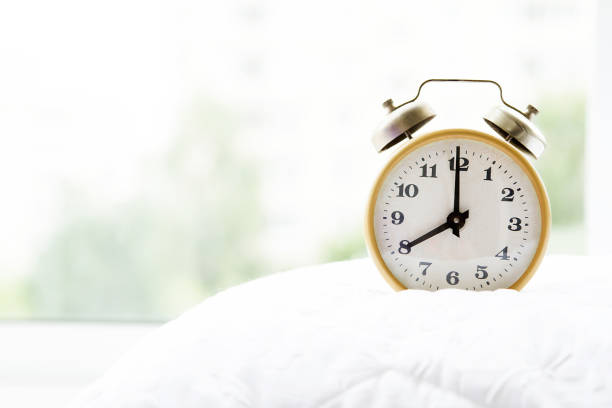 ウィンドウの前面に、枕の上の目覚まし時計 - oversleep ストックフォトと画像