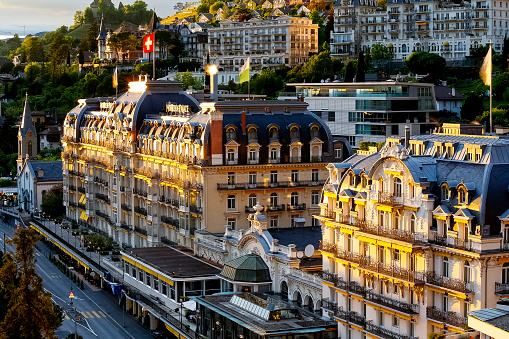 Montreux, Switzerland - 22 May 2013: A bird's eye view of the front facade of the famous five-star luxury hotel (Fairmont Le Montreux Palace). The hotel was built in 1906 and is located on High Street (Grand Rue) and offers a luxurious stay for guests arriving on the Swiss Riviera in Montreux. Above the hotel on the slope you can see many other buildings of the city.