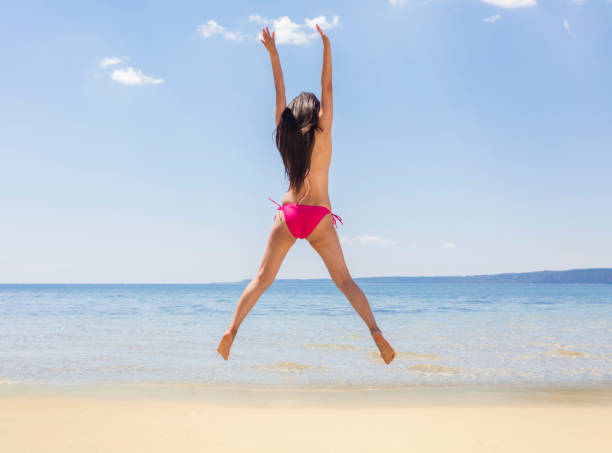 istock Happy young woman jumping on beach 1007957890