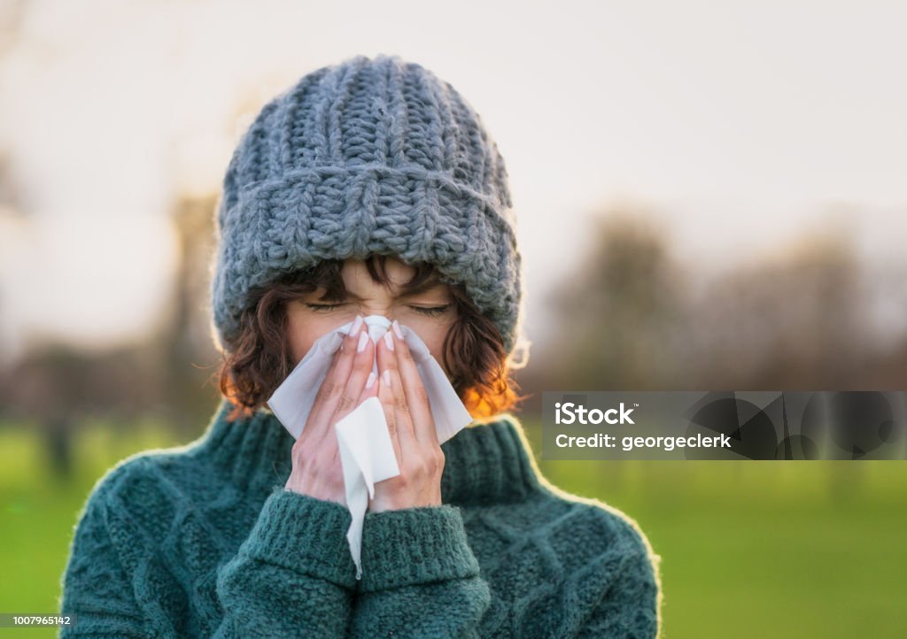 Coping with a winter cold Close-up of a woman suffering from the symptoms of a cold outdoors during winter. Cold And Flu Stock Photo