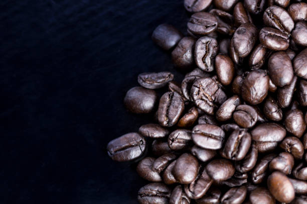 istock Brown coffee beans on black surface. Top view close up. 1007974186