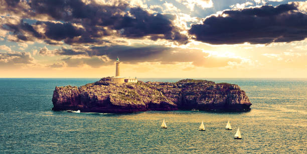 Seascape of sunset and wonderful sky. Boats sailing in the ocean Lighthouse on the sea over the rocks in Cantabria, Santander, Spain cantabria photos stock pictures, royalty-free photos & images