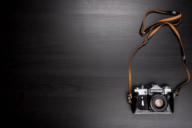 istock Vintage Camera Isolated on Black Wooden Background 1007985648