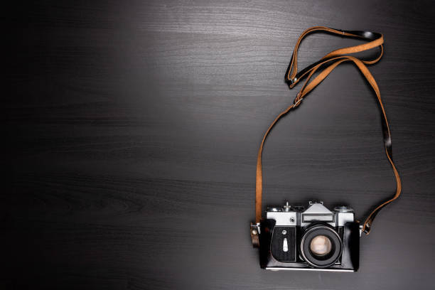 istock Vintage Camera Isolated on Black Wooden Background 1007986788