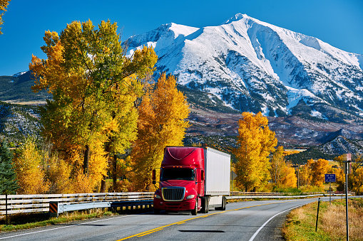Red truck on highway in Colorado at autumn, USA. Mount Sopris landscape.