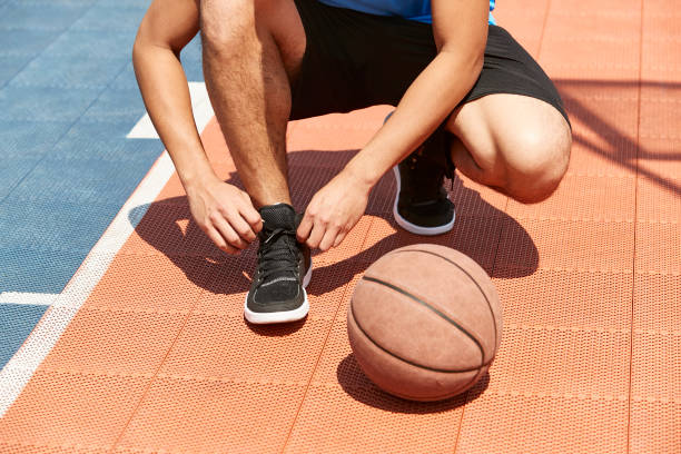 young asian basketball player lacing up young asian adult lacing up and getting ready to play basketball. lace up stock pictures, royalty-free photos & images