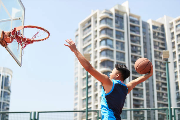 istock young asian basketball player slam dunking 1007991024