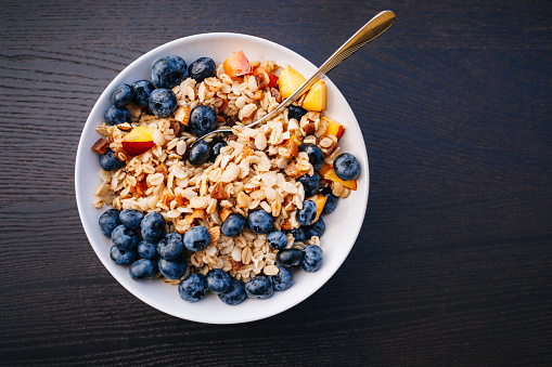 Healthy breakfast food with granola, yogurt, fruits and nuts. Dessert parfait with dried fruits for breakfast.