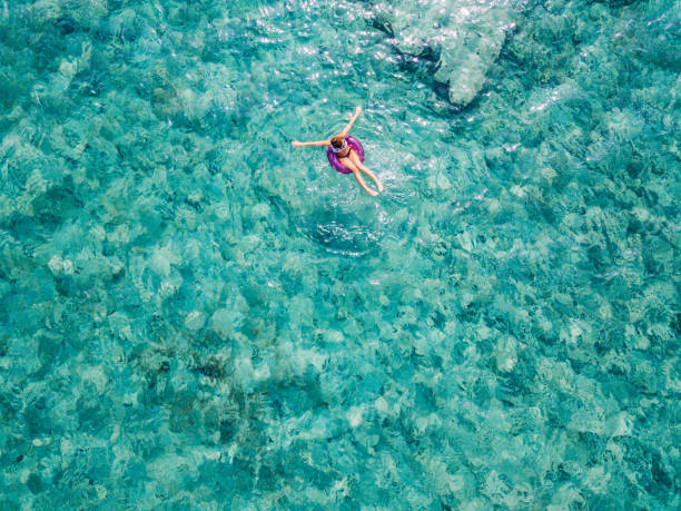 istock Young woman in bikini floating on blue sea 1008002244