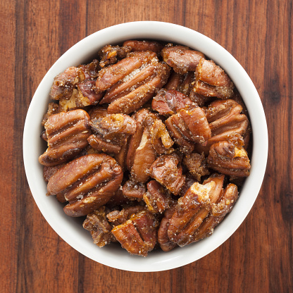 Top view of white bowl full of candied pecans