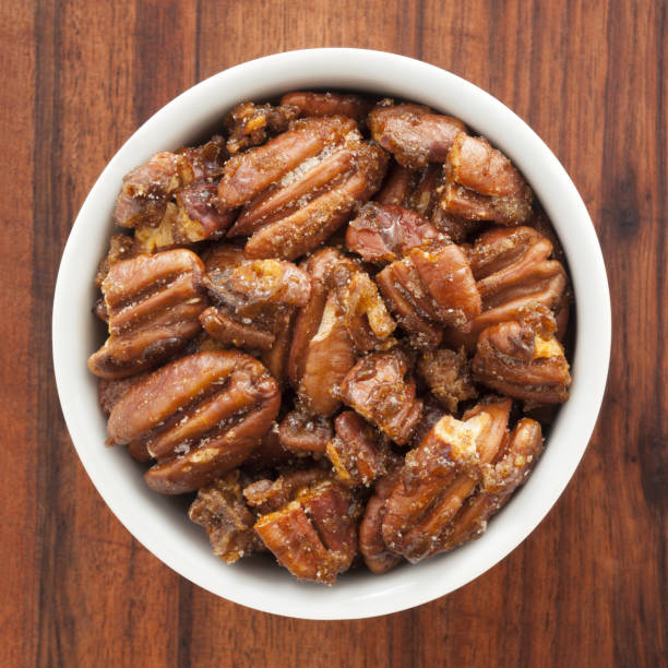 Candied pecans Top view of white bowl full of candied pecans candied fruit stock pictures, royalty-free photos & images