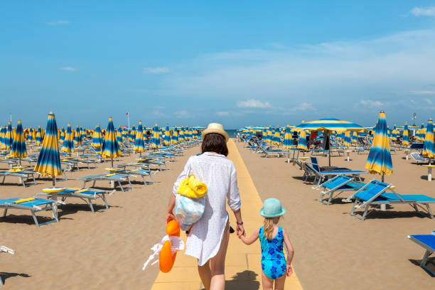 Woman and child outdoors Woman and child outdoors. Mother and daughter going to rest on beach. Rimini, Italy. rimini stock pictures, royalty-free photos & images