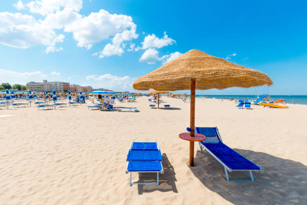 Beach with clean white sand Beach with clean white sand. Rimini beach on a sunny day. Sun umbrella and deck chairs on seaside on blue sky background. rimini stock pictures, royalty-free photos & images
