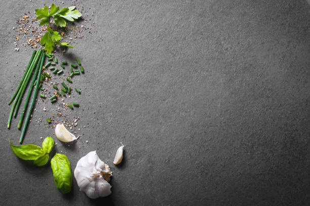 top down view on kitchen ingredients like garlic, basil, spices and herbs on slate stone, with free space in the middle and right side - down view imagens e fotografias de stock