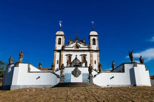Bom Jesus de Matosinhos sanctuary with the twelve prophets by the brazilian baroque artist Aleijadinho at Congonhas, Minas Gerais, Brazil under dark blue sky and full sun.