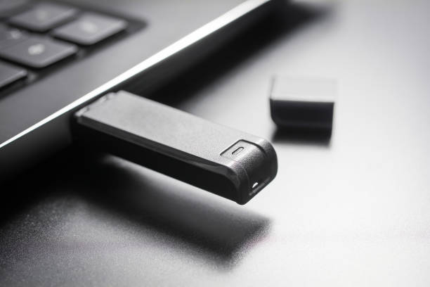 Macro Of A Black USB Memory Stick Plugged Into The USB Port Of A Black Laptop, Side View stock photo