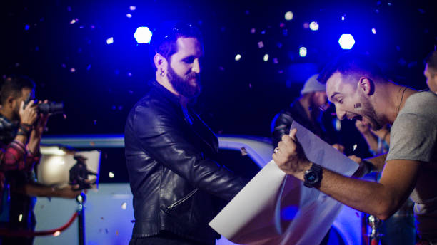 Musicians giving autographs to fans Cool rock band giving autographs to fans on poster on red carpet of celebrity event and makes photo celebrity fans stock pictures, royalty-free photos & images