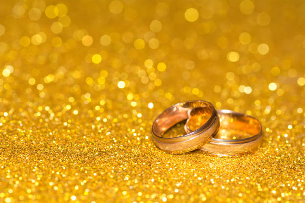 istock Wedding rings on a golden radiant background. Glitter shine 1008080388
