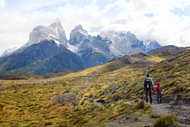 family of two, father and son, enjoying gorgeous view of cuernos del paine in torres del paine national park in chile, active family vacation concept