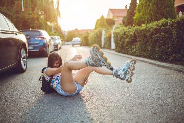 Girl falls while driving roller skates down the street. Young brunette woman loosing balance and falls while driving inline skates downtown. falling behind stock pictures, royalty-free photos & images