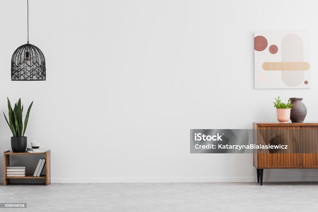 Retro, gabinete de madera y una pintura en un salón vacío interior con paredes blancas y copia espacio para un sofá. Foto real. - Foto de stock de Pared libre de derechos