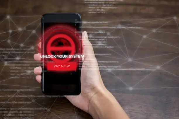 Hand holding smartphone that the system being locked by ransomware cyber attack