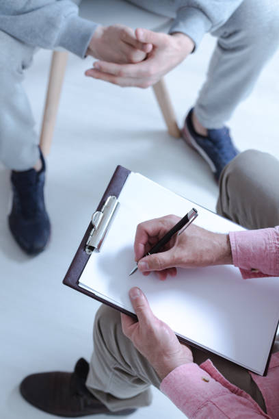 High view of a man's hand holding a pen and writing on a paper during a meeting High view of a man's hand holding a pen and writing on a paper during a meeting school sport high up tall stock pictures, royalty-free photos & images