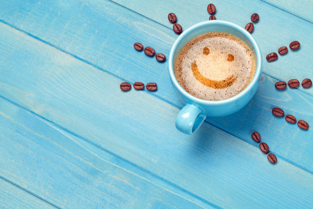 푸른 나무 테이블에 웃는 얼굴로 커피 컵 - cappuccino coffee breakfast freshness 뉴스 사진 이미지
