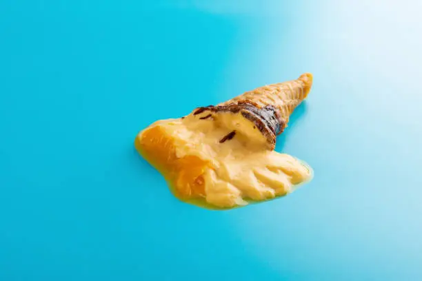 mini mango or orange flavor ice cream cone melting on blue background