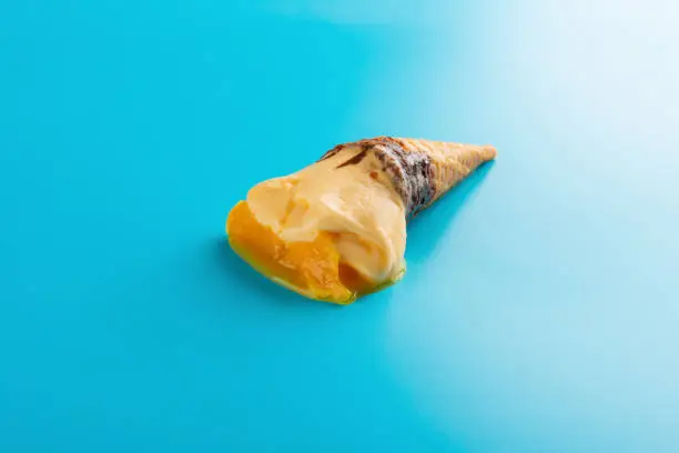 mini mango or orange flavor ice cream cone melting on blue background