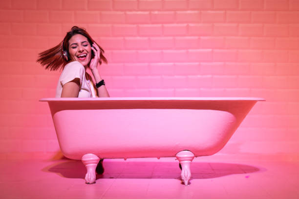 femme ayant plaisir et danse dans la baignoire rose - soaking tub photos et images de collection