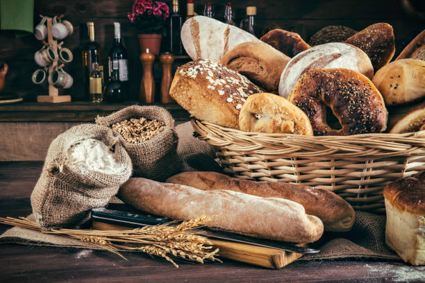 Artisanal bakery: Fresh mixed Bun, rolls and ingredients Artisanal bakery: Group of fresh mixed breads and rolls. Artisanal bakery is bread made by a craftsperson using mainly traditional techniques. Also, it is usually made by hand, however, many artisanal bakeries use also electrical mixers and dividers. The bakers who do everything by hand tend to draw a line differently than the bakers who use lots of automated equipment. Artisanal bakery, only made by hand, is part of the romantic and traditional way of cooking from old times. bun bread stock pictures, royalty-free photos & images