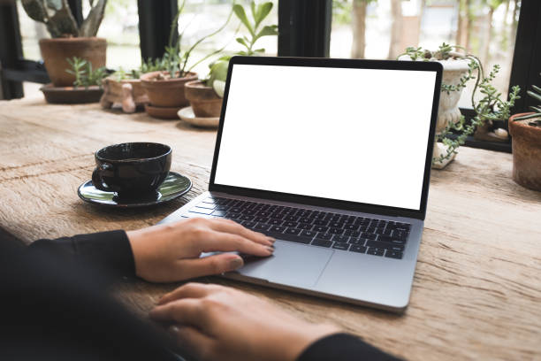 istock Mockup image of hand using and typing on laptop with blank white desktop screen on vintage wooden table in cafe 1008161552