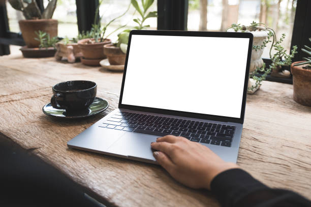 istock Mockup image of hand using and typing on laptop with blank white desktop screen on vintage wooden table in cafe 1008161572