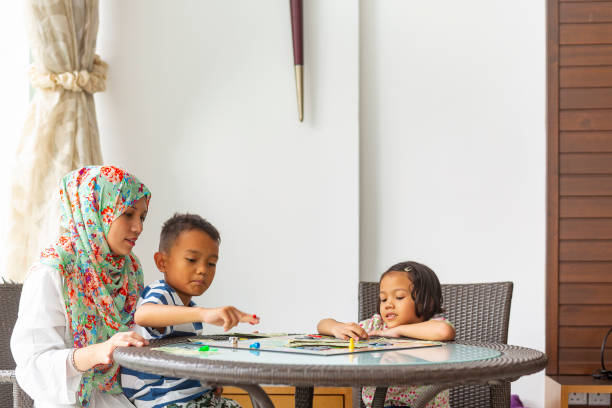 Asian Muslim Family Playing a Board Game Together