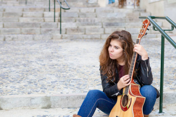 istock Cheerful female street performer testing guitar sound 1008207632