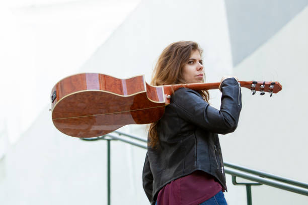 istock Serious female guitar player walking outdoors 1008207680
