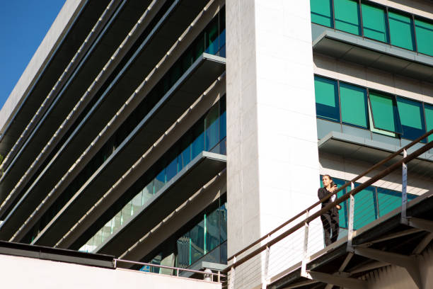 Four professionals gather on a balcony, discussing project plans while enjoying the bright sunlight.