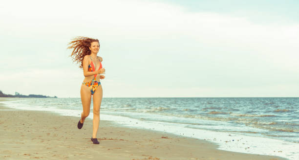istock Attractive woman runs on sand beach in summer. 1008213018