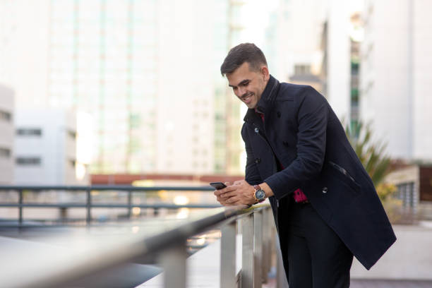istock Cheerful handsome Hispanic man smsing on smartphone 1008220386