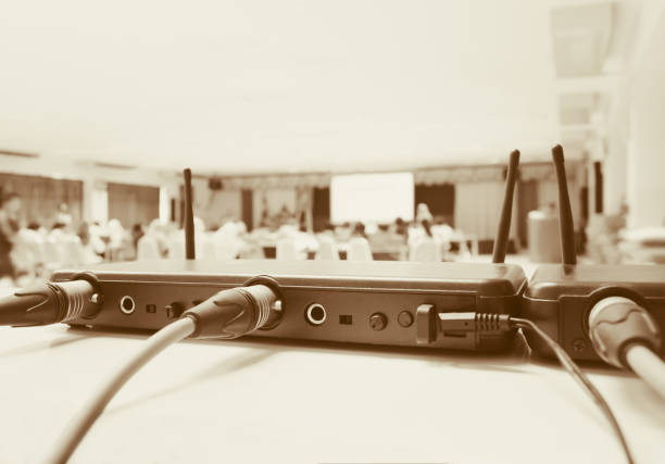 istock Close up Jack plug cables connected with old box of wireless microphone in conference meeting room seminar business blur. Vintage color tone 1008222926