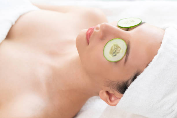 Relaxed young woman getting eye nature treatment by cucumber at luxury spa resort. Wellness and healing concept.