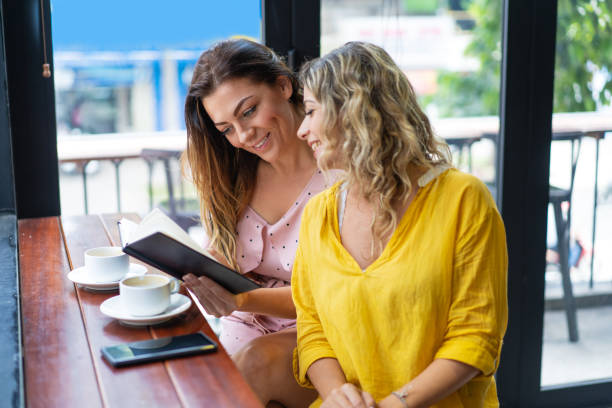 istock Pretty women reading book and drinking coffee in cafe 1008223438