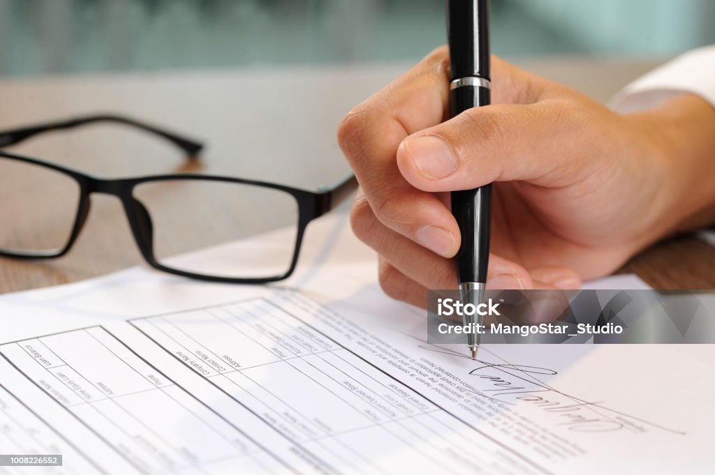 Closeup of woman signing document Closeup of woman signing document. Contract and glasses lying on table. Deal concept. Cropped view. Document Stock Photo